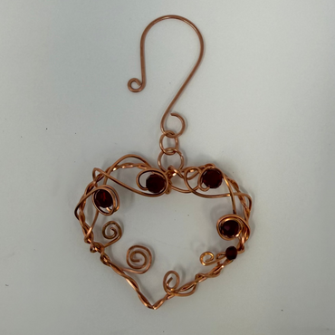 Copper heart-shaped ornament with beads on a white background