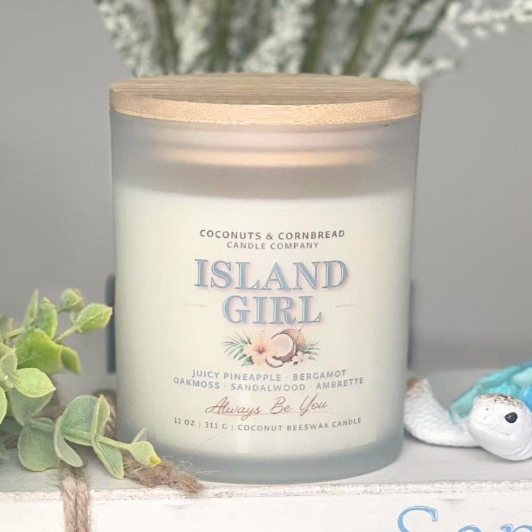 Candle and wax melts labeled 'Island Girl' on a decorative shelf with plants and ocean-themed decor.