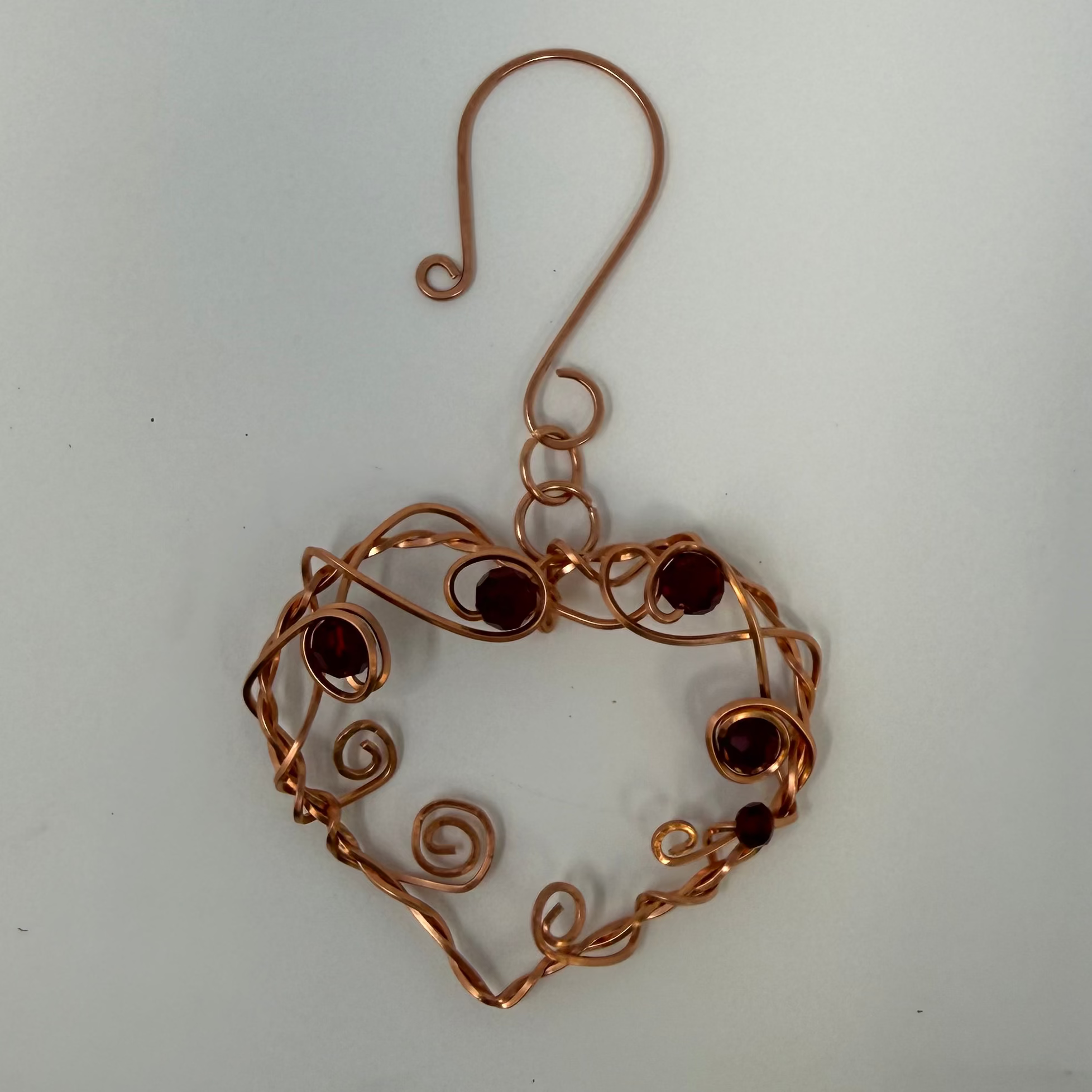Copper heart-shaped ornament with beads on a white background