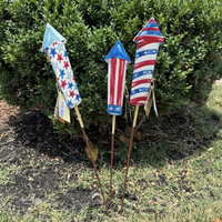 Decorative patriotic rocket-shaped stakes in a garden setting.