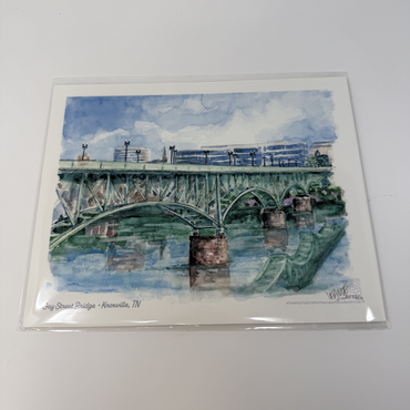 Watercolor painting of a bridge over water with a blue sky, on a white background.